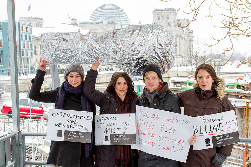 Vier Personen halten im verschneiten Berlin vor dem Reichstag einen silbernen Schlüssel hoch. Sie haben außerdem weiße Schilder auf denen steht: „Datensammler sind Verbrecher“, „Generalverdacht ist Mist“, sowie Passwörter für WLAN und Online-Banking.