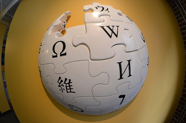 Ein weißer Puzzleball mit W, Omega und weiteren Symbolen für die Wikipedia. In einem fehlenden Puzzleteil steht ein Mini-Stormtrooper.